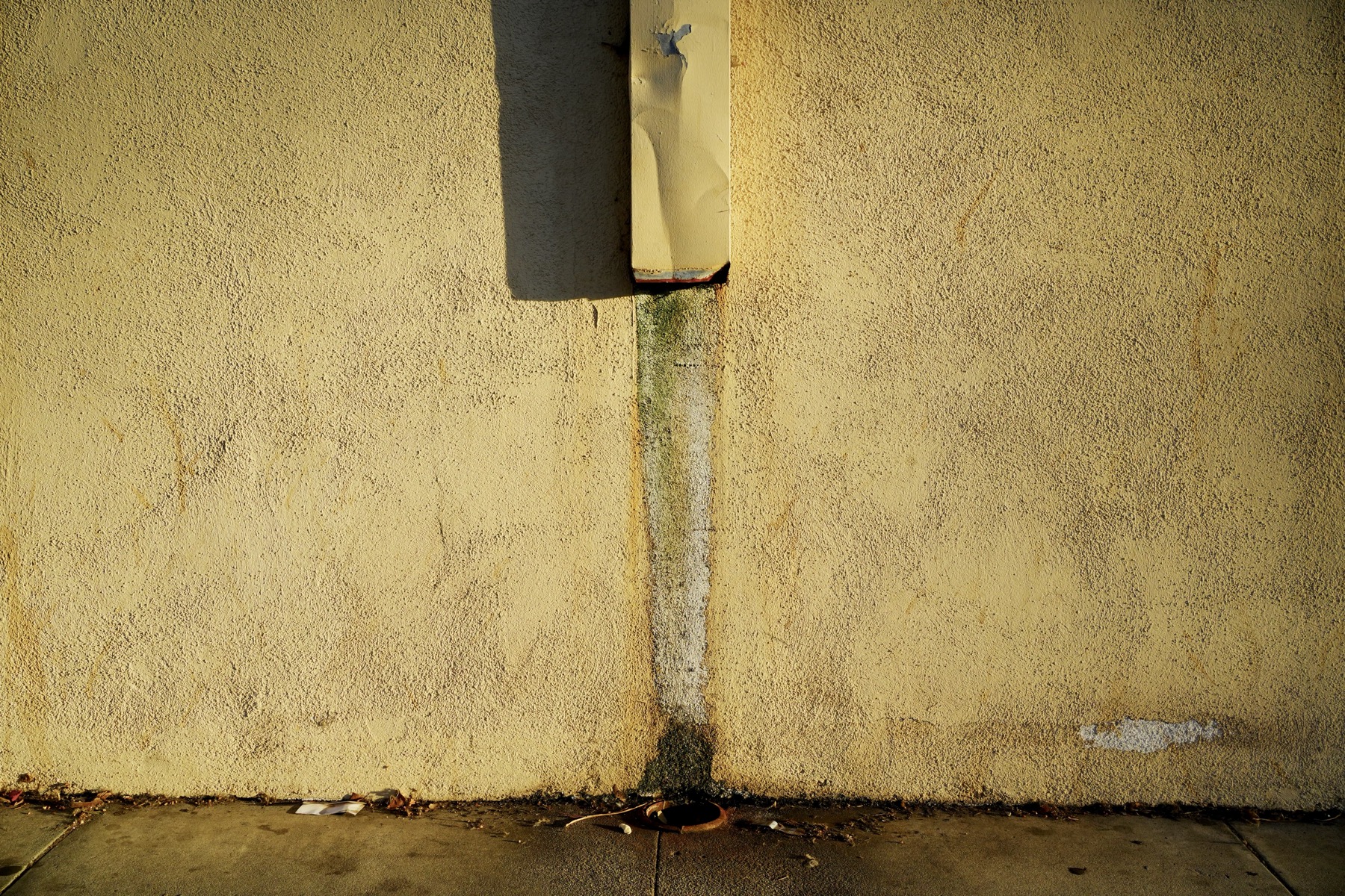 A missing downspout piece that connects the upper segment to the drain in the ground.