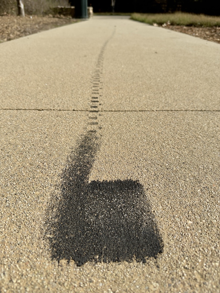 An e-bike tire mark left on the sidewalk forms an improbable fat square before trailing off into the distance with tread prints.